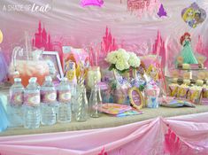 a table topped with lots of princess themed items and desserts on top of it