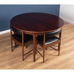 a wooden table with two black leather chairs next to it on a hard wood floor