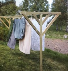 clothes hanging out to dry on a clothesline in the grass near some trees and bushes