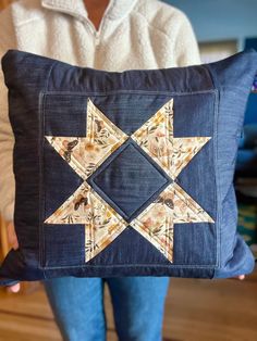 a woman holding a blue pillow with an embroidered star on it