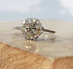 a diamond ring sitting on top of a piece of wood