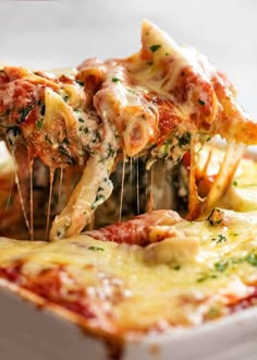 a piece of lasagna being lifted from a casserole dish