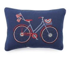 a blue pillow with a red bicycle on it and an american flag in the back