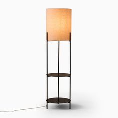 a floor lamp with a white shade on the top and a black stand underneath it