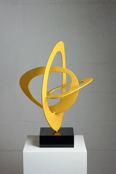 a yellow sculpture sitting on top of a white pedestal