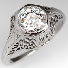 an antique style diamond ring with filigrees on the band and center stone