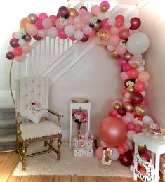 a bunch of balloons that are on the ground near a chair and stairs in a room