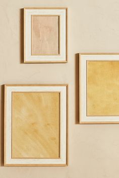 three wooden frames hanging on the wall with one empty and one unpainted