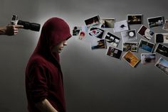 a person in a red hoodie holding a camera and pointing at pictures on the wall