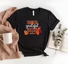 Celebrate the spirit of Thanksgiving with this vibrant shirt featuring the words "Thankful, Grateful, Blessed" in bold, cheerful fonts. A cute turkey peeks around the side, showcasing bright fall colors like orange, red, and yellow, capturing the warmth and joy of the season. 📢How Do I Order 1) Before you place the order, please review all the information. 2) From the drop down menu, chose your shirt type and size. 3) From the drop down menu, chose the color of the shirt. 4) If you need more it Inspirational Crew Neck T-shirt For Fall, Inspirational Graphic Print T-shirt For Fall, Letter Print T-shirt As Fall Gift, Fall Graphic Tee With Lettering, Bright Fall Colors, Small Business Design, Cute Turkey, Thankful Shirt, Clothes Fall