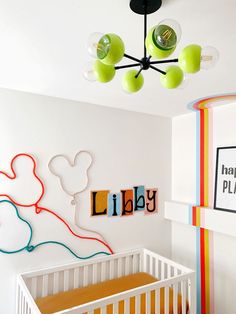 a baby's room with a crib, lamp and artwork on the wall