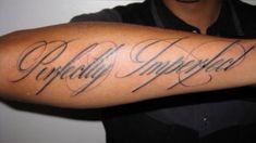 a man with a tattoo on his arm that says perfectly imperfected in cursive writing