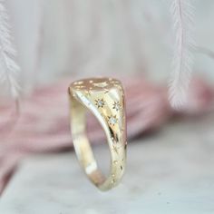 a close up of a gold ring on a white surface with feathers in the background