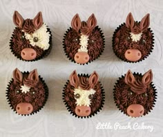 four cupcakes decorated with chocolate frosting and farm animals'heads on them