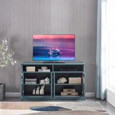 a flat screen tv sitting on top of a wooden cabinet in a living room next to a potted plant