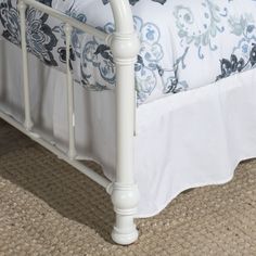 a white metal bed with blue and white bedspread