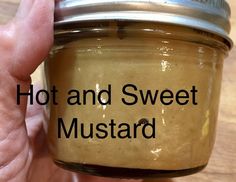 a hand holding a jar of mustard with the words hot and sweet mustard