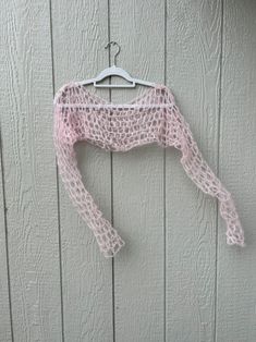 a pink sweater hanging on a wooden wall