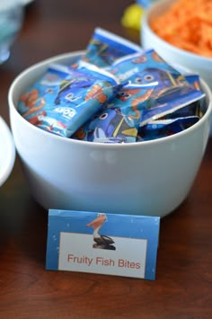 a bowl filled with fruity fish bites next to bowls of carrots and other snacks