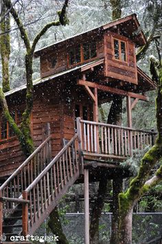 a cabin in the woods with stairs leading up to it and snow falling on the ground