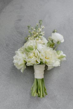 a bouquet of white flowers sitting on top of a gray table next to a wall