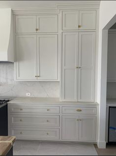 an empty kitchen with white cabinets and marble counter tops in the middle of the room