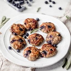 blueberry muffins on a white plate with sage leaves