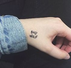 a person's hand with a small tattoo on the wrist that says bad wolf