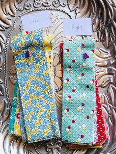 four different colored ties sitting on top of a metal tray with paper attached to them