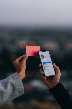 two people are holding up their cell phones and one has a red card in front of them