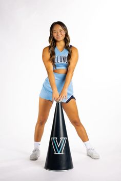 a woman in a cheerleader outfit is posing with a cone shaped object on her feet