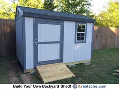 a small shed sitting in the grass next to a fence