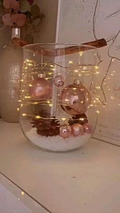 a glass vase filled with ornaments on top of a white counter next to a plant