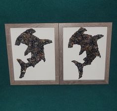 two pieces of paper cut out of the shape of fish are displayed in a wooden frame