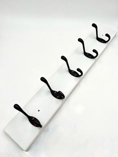 four black hooks are attached to a white board