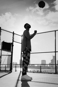 a man standing in front of a fence throwing a frisbee