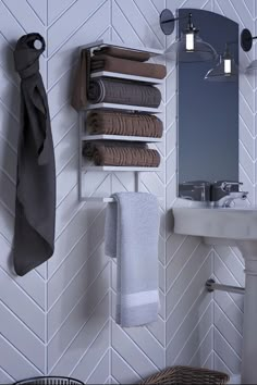 towels are hanging on the wall next to a sink and mirror in a white tiled bathroom