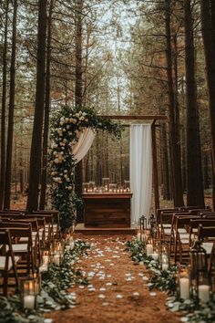 an outdoor ceremony setup with white flowers and greenery on the aisle, surrounded by candles