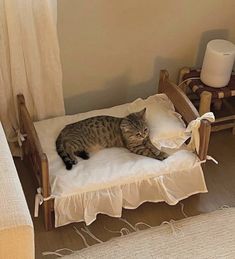 a cat laying on top of a wooden chair next to a bed in a room