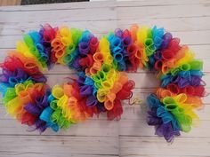 a multicolored wreath made out of mesh on a wooden wall with the word love written in it