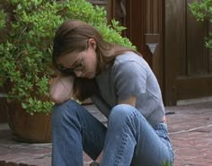 a woman sitting on the ground with her head in her hands