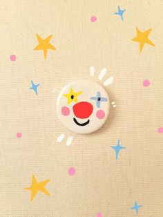 a button with a clown's face and stars on the ground in front of it