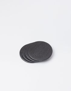 three black coasters sitting on top of each other