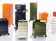 several different colored boxes on wheels with handles and drawers in the middle one is empty