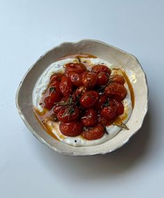 a white bowl filled with tomatoes on top of a table