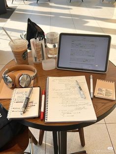 a laptop computer sitting on top of a wooden table next to a notebook and pen