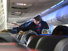 a woman standing in the aisle of an airplane with her hand out to someone else