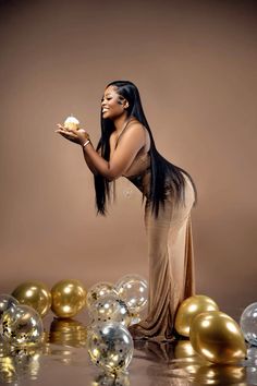 a woman holding a piece of food in her hand while standing next to balloons and confetti