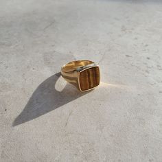 a gold ring with a tiger's eye stone in the center on a white surface