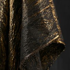 a black and gold fabric with metallic foiling on the edges, as if it were folded over